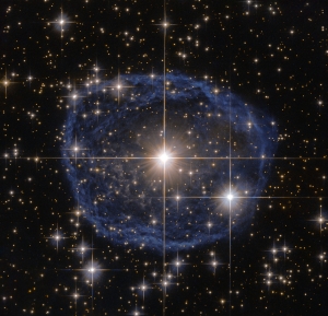 Sparkling at the centre of this beautiful NASA/ESA Hubble Space Telescope image is a Wolf–Rayet star known as WR 31a, located about 30 000 light-years away in the constellation of Carina (The Keel). The distinctive blue bubble appearing to encircle WR 31a, and its uncatalogued stellar sidekick, is a Wolf–Rayet nebula — an interstellar cloud of dust, hydrogen, helium and other gases. Created when speedy stellar winds interact with the outer layers of hydrogen ejected by Wolf–Rayet stars, these nebulae are frequently ring-shaped or spherical. The bubble — estimated to have formed around 20 000 years ago — is expanding at a rate of around 220 000 kilometres per hour! Unfortunately, the lifecycle of a Wolf–Rayet star is only a few hundred thousand years — the blink of an eye in cosmic terms. Despite beginning life with a mass at least 20 times that of the Sun, Wolf–Rayet stars typically lose half their mass in less than 100 000 years. And WR 31a is no exception to this case. It will, therefore, eventually end its life as a spectacular supernova, and the stellar material expelled from its explosion will later nourish a new generation of stars and planets.